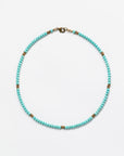 A Designs By Raya turquoise beaded necklace with intricate gold accents arranged intermittently, displayed against a plain white background, embodying Arizona style.