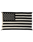 The Black and White American Flag by Savarin & Co is a handcrafted wool decor piece featuring black and white stripes with fifty stars on a black background in the top left, creating an elegant and striking home accent.