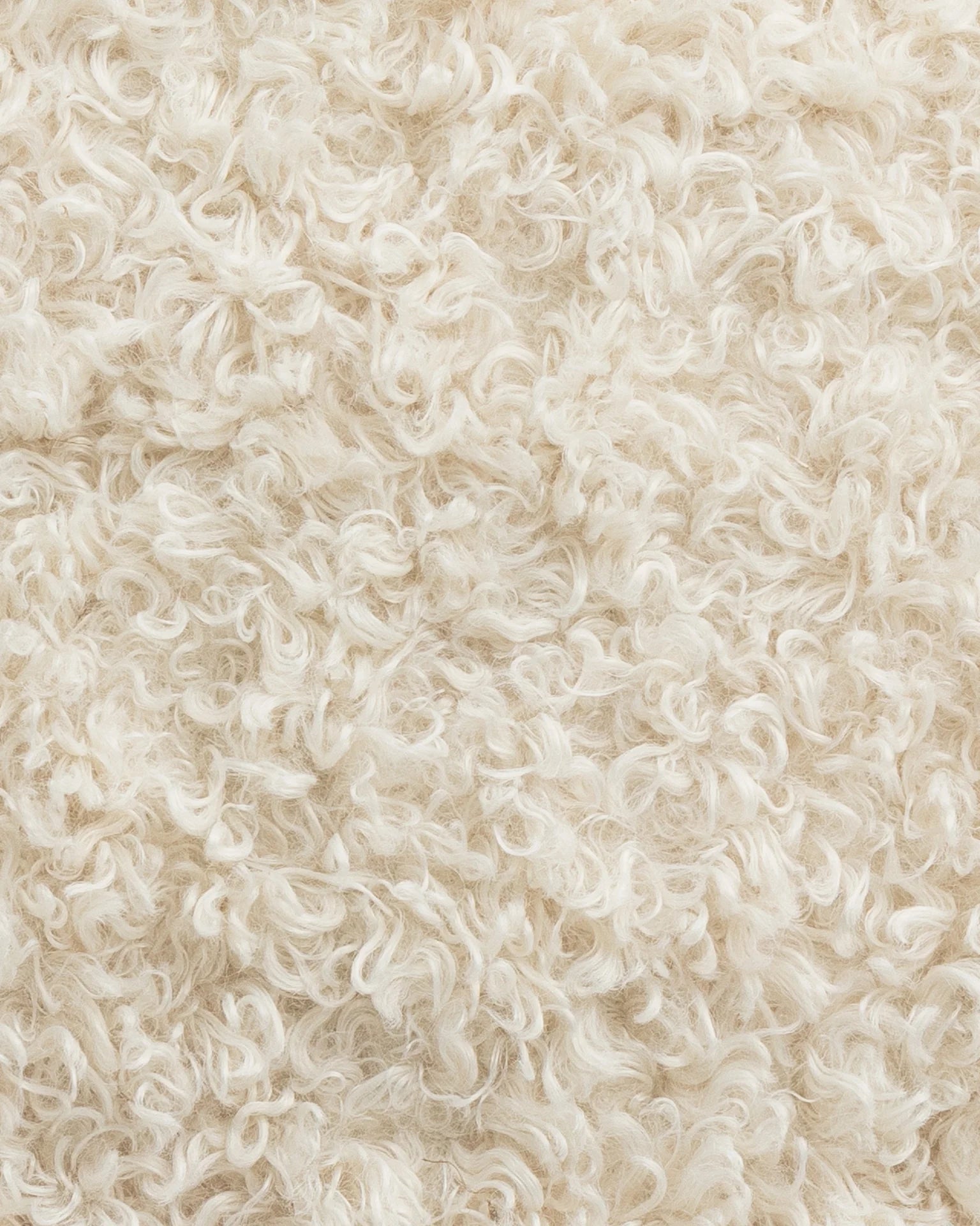 Close-up view of a textured, curly sheepskin rug in a light cream color, showing intricate curly wool fibers in a Gabby bungalow.