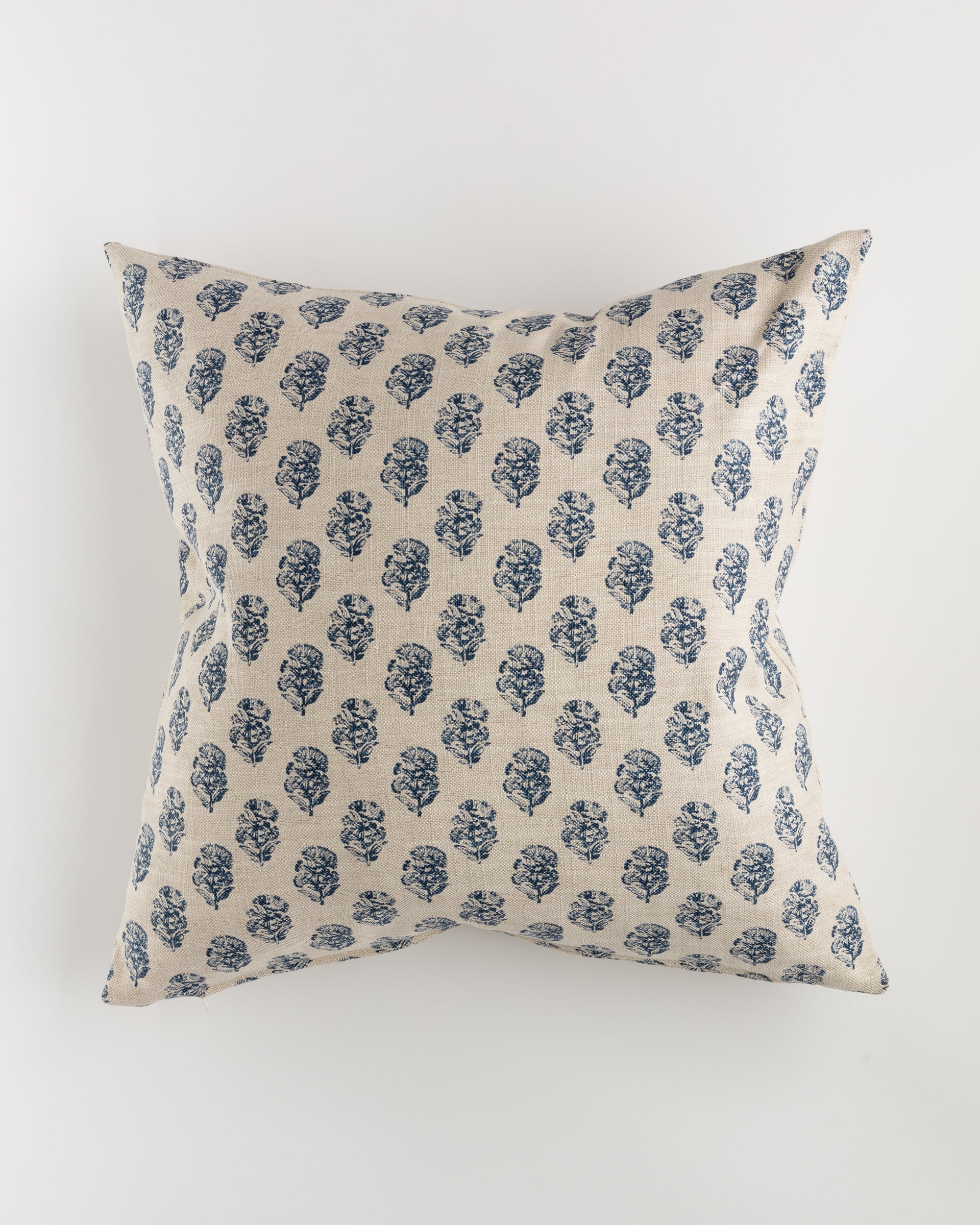 The Custom 1 Pillow 28x28 by Pindler features a square, beige background adorned with a pattern of small blue floral designs. Centered against a plain white backdrop, this luxurious pillow exemplifies intricate detailing and minimalist elegance.