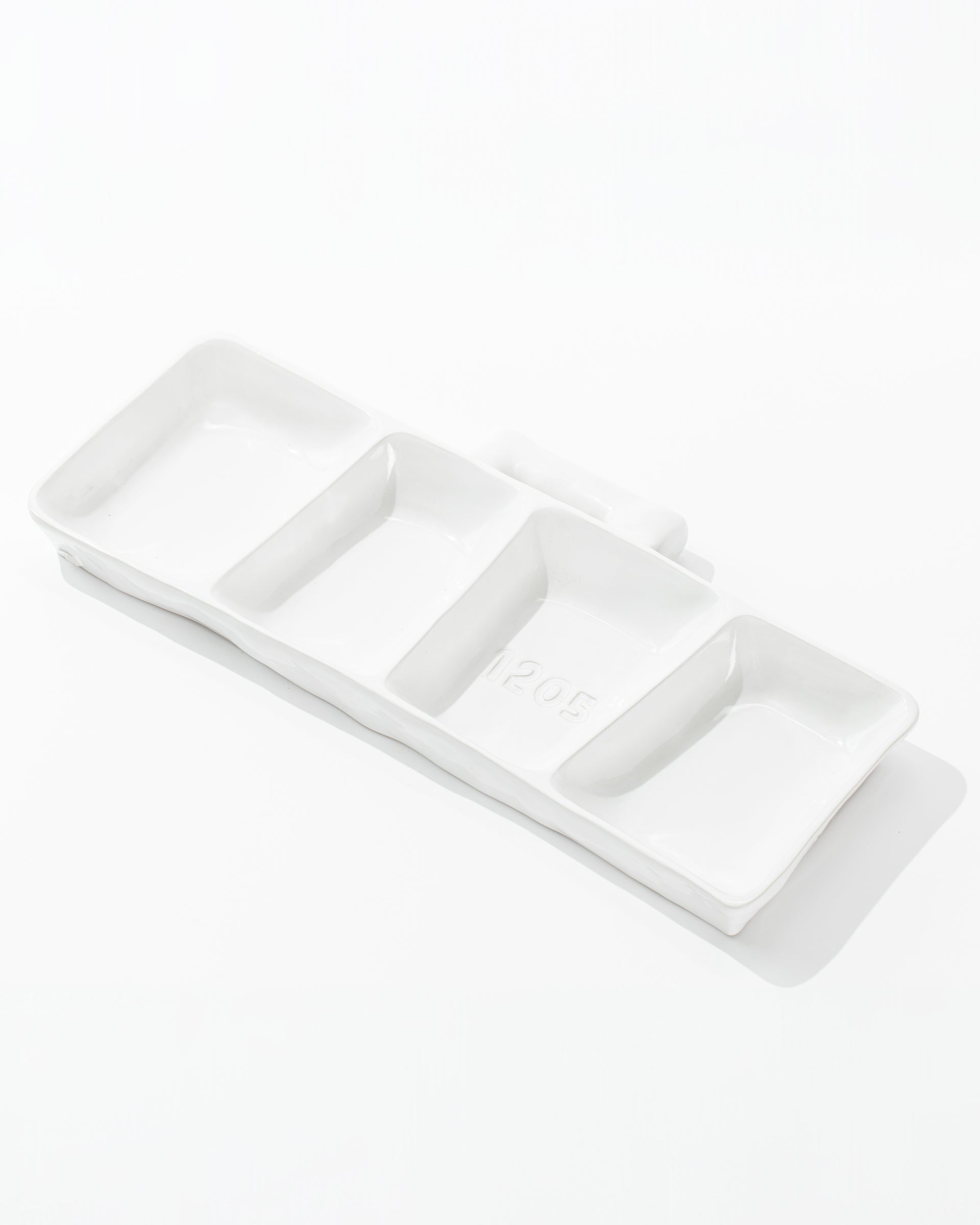 The 5455 Appetizer Platform No. 455 by Montes Doggett is a white, rectangular, handmade ceramic dish featuring three equally sized compartments arranged in a row. It has smooth surfaces and raised edges, making it ideal for serving condiments, sauces, or small appetizers.