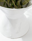 A close-up of a high-fired ceramic Catchall Bowl No. 979 with a wide rim and narrow base from Montes Doggett. Inside the bowl, there are green leafy branches. The glossy surface gleams, set against a bright white background. Artisan crafted in Peru, this piece features a small circular logo with the letters 'MD' at the base.