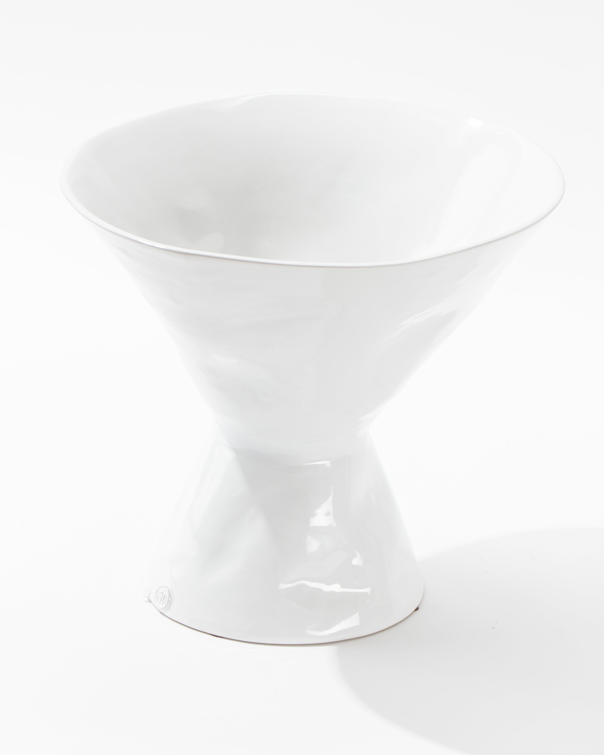 Introducing the Catchall Bowl No. 979 by Montes Doggett – a white, modern ceramic bowl with a unique hourglass shape. The design features a narrow middle section with wide, flaring openings at both the top and bottom. Crafted in Peru, this bowl boasts a glossy finish and is showcased on a plain, white background in the photograph.