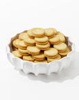 A bowl of golden sandwich cookies, each boasting an intricate pattern on the top biscuit with a layer of cream in the middle, is showcased in Montes Doggett's Bowl No. 727—a white, high-fired ceramic piece featuring a scalloped edge and crafted in Peru. The elegant bowl stands out against a simple white background.