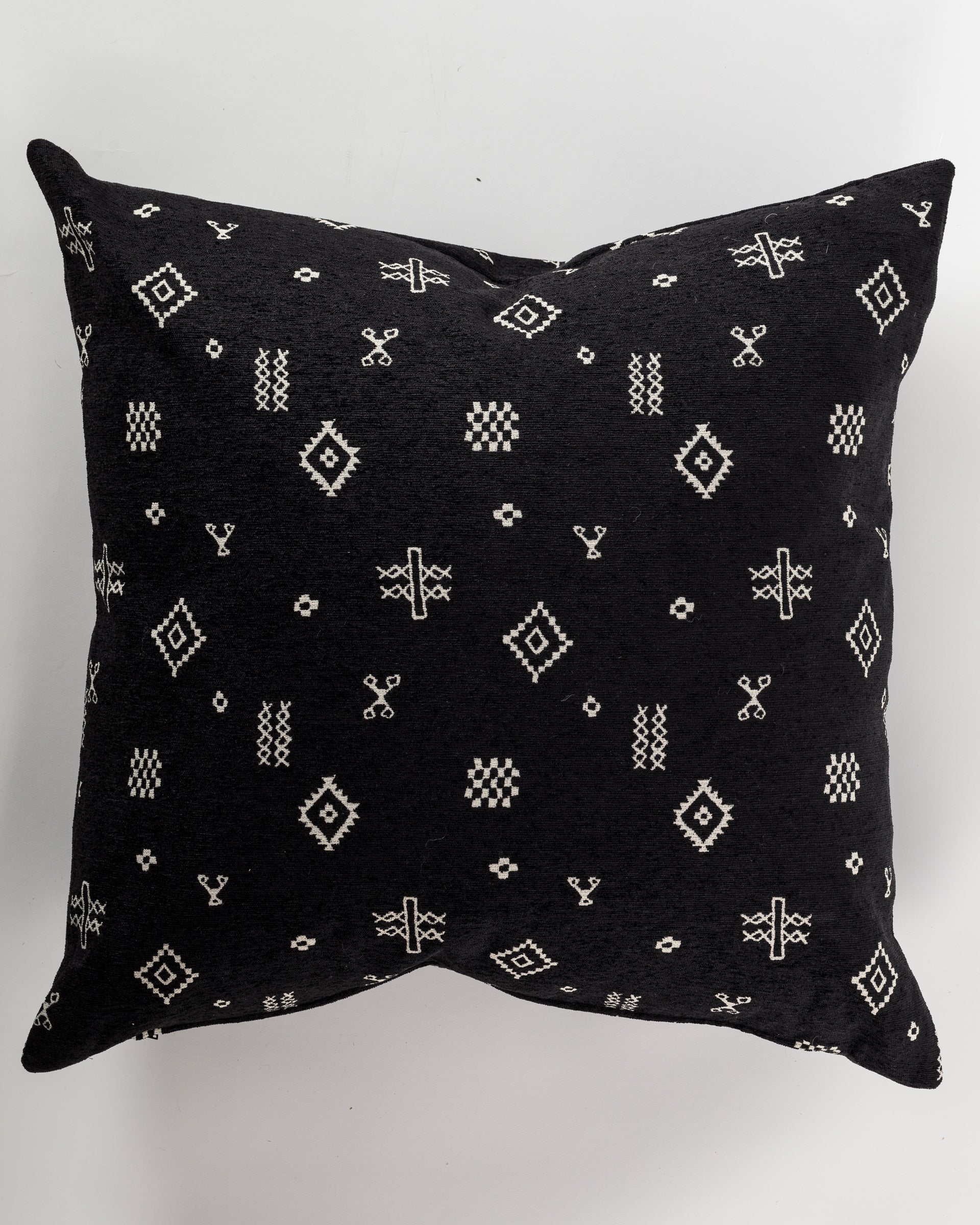 The Custom 1 Pillow 28x28 by Pindler is a luxurious black euro pillow adorned with intricate white geometric and tribal patterns, including diamond shapes and cross-like symbols, providing a striking contrast against its dark background.