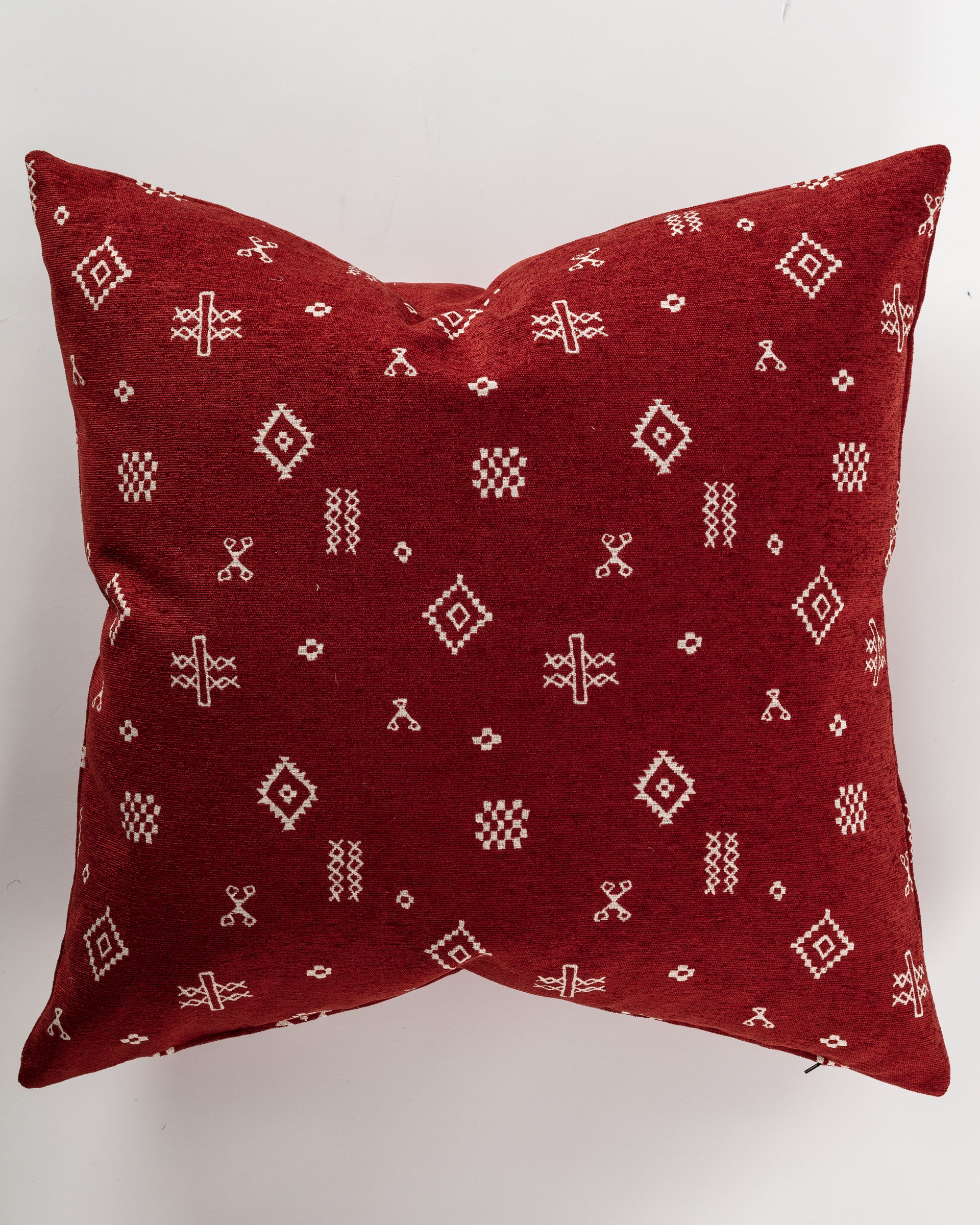 The elegant Custom 1 Pillow 28x28 from Pindler features a rich maroon color adorned with white geometric tribal patterns on a plain background. The detailed designs, such as diamond shapes and crosses, enhance its decorative allure. Ideal for a euro pillow setup, it comes with a comfortable pillow insert for extra coziness.