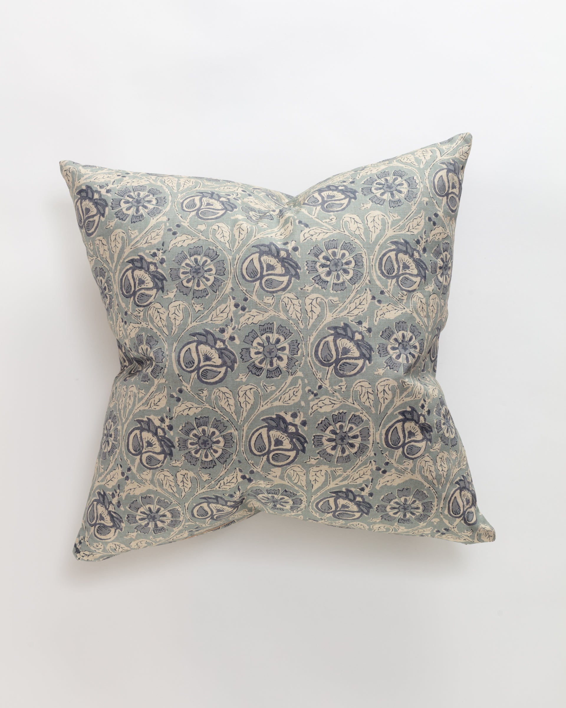 The Norwalk Carrie Pillow is a square cushion with a light blue floral pattern on an off-white background, showcasing intricate vine and flower motifs. This ultra-luxurious throw pillow provides relaxing comfort and sits elegantly centered on a plain white surface.