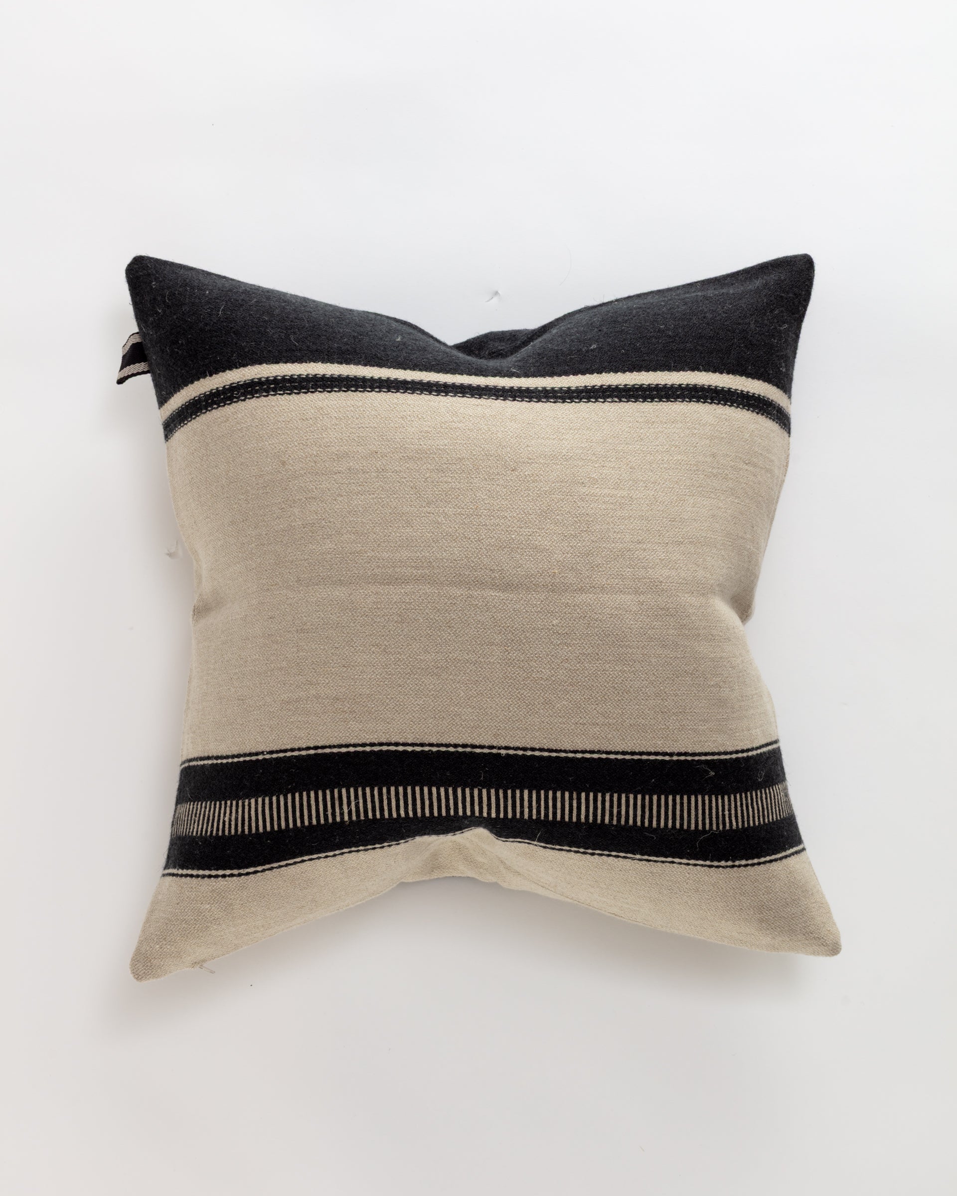 The Marshall Pillow by Libeco Home offers a timeless, minimalist design with black and off-white horizontal stripes on a light background. Made of luxurious linen and wool, its center is predominantly light and framed by two dark sections at the top and bottom.