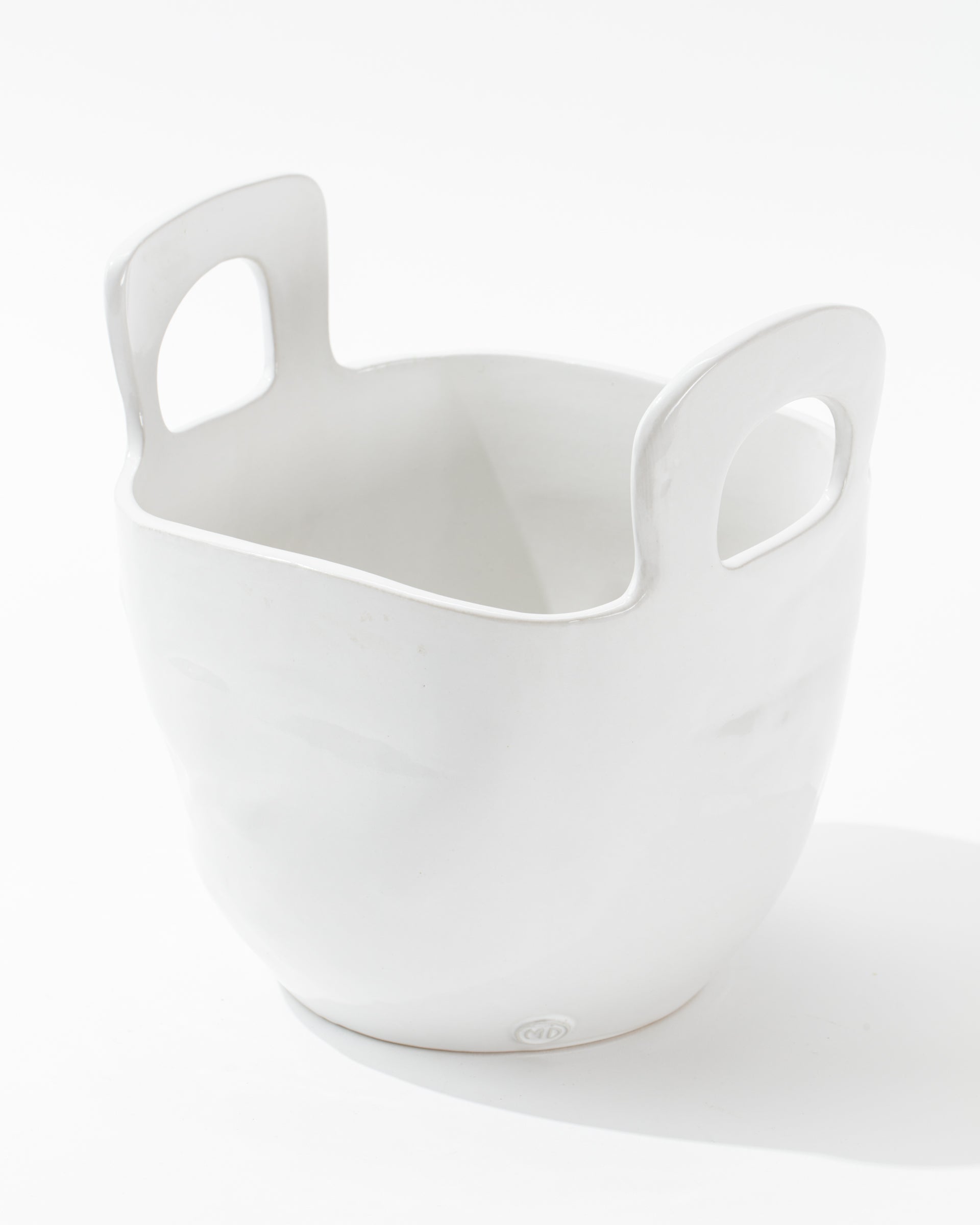 The 4994 Bowl no. 994 by Montes Doggett is a white ceramic container with a smooth finish, featuring two large handle openings on opposite sides near the top. Handmade in Peru, this high-fired ceramic piece has a broad, rounded base and tapers slightly toward the top, giving it a modern, minimalist design.