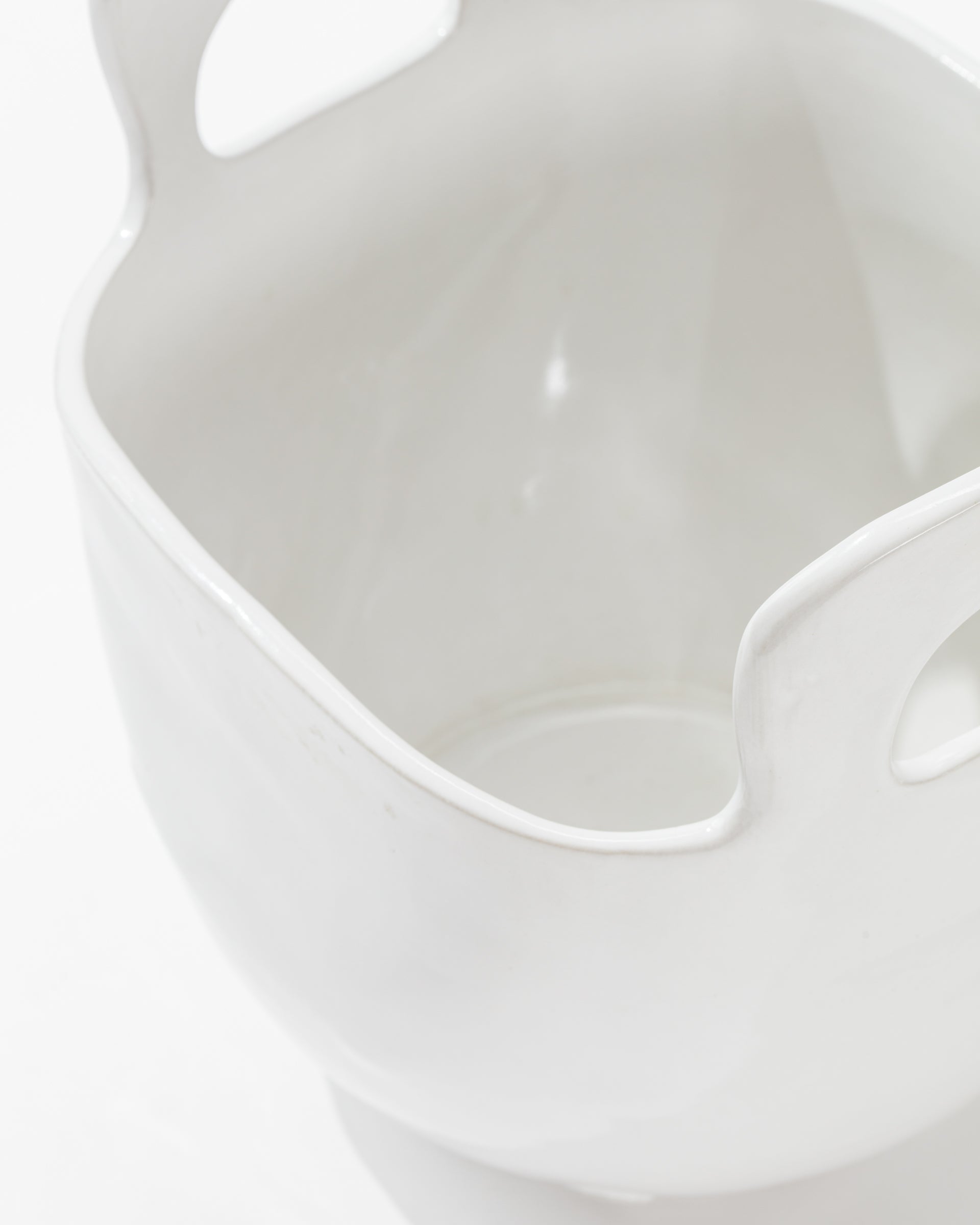 Close-up image of Montes Doggett&#39;s 4994 Bowl no. 994, a high-fired ceramic container with a smooth, glossy finish. This sculptural statement piece features two large, curved handles on opposite sides and a wide, open mouth. Handmade in Peru, the white background highlights the container&#39;s intricate details clearly.