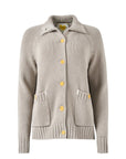 The Joy Sweater Coat by Kerri Rosenthal is a beige knit cardigan featuring yellow buttons, front pockets, and a collar. It includes ribbed cuffs and hem for a cozy and stylish look, while its chunky cotton material boasts subtle multicolor embroidery that adds an artistic flair to the plain white background.