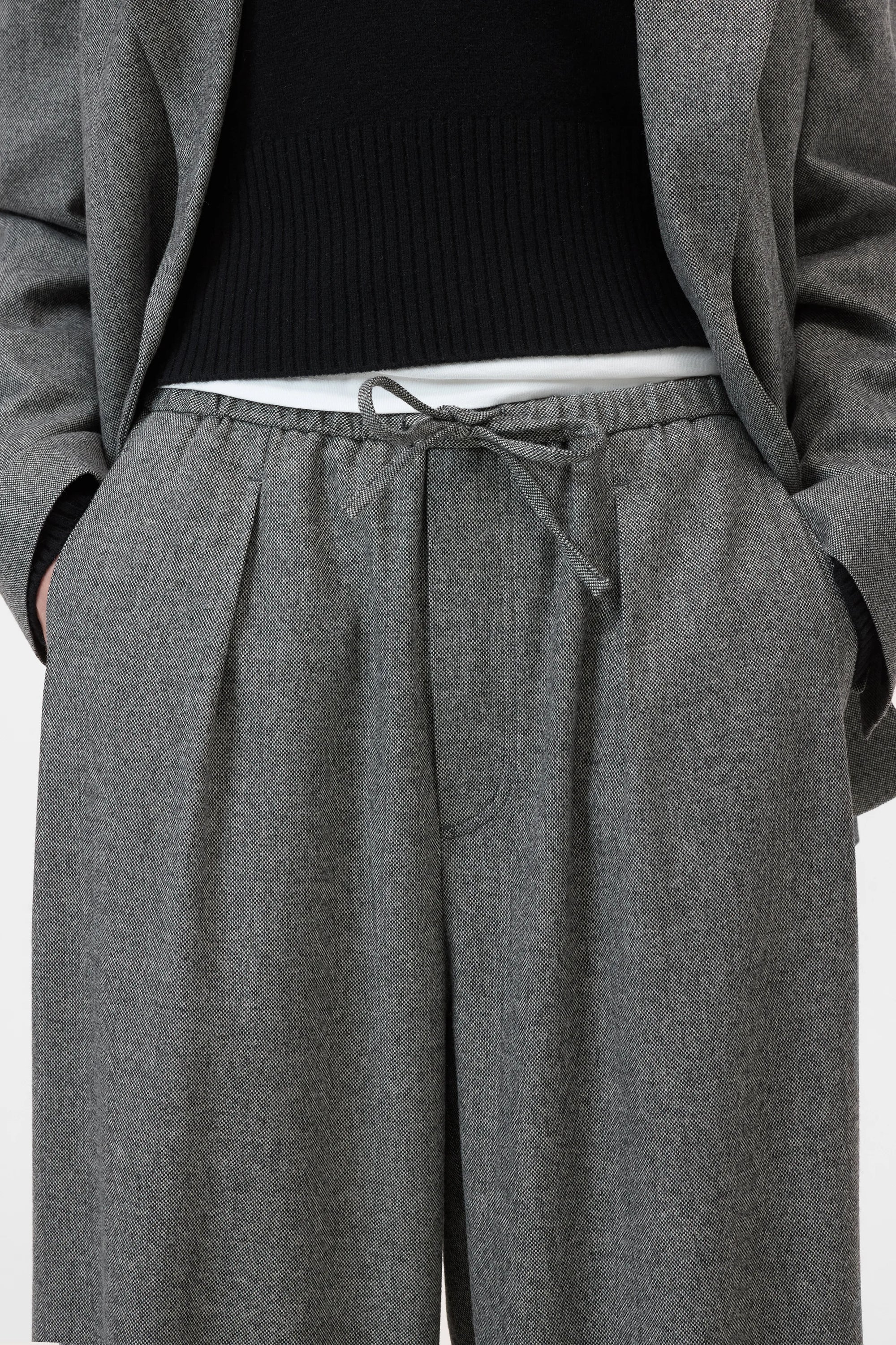 Grey CLOSED Wynston relaxed fit flannel trousers styled with a black sweater and grey blazer, hands in pockets.