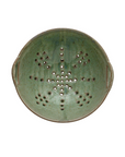 A round, aqua Creative Co-op Berry Bowl made of stoneware, viewed from above. The reactive glaze colander has a pattern of holes arranged in a star shape in the center, with additional holes around the perimeter. It features two small, grooved handles on opposite sides for gripping.