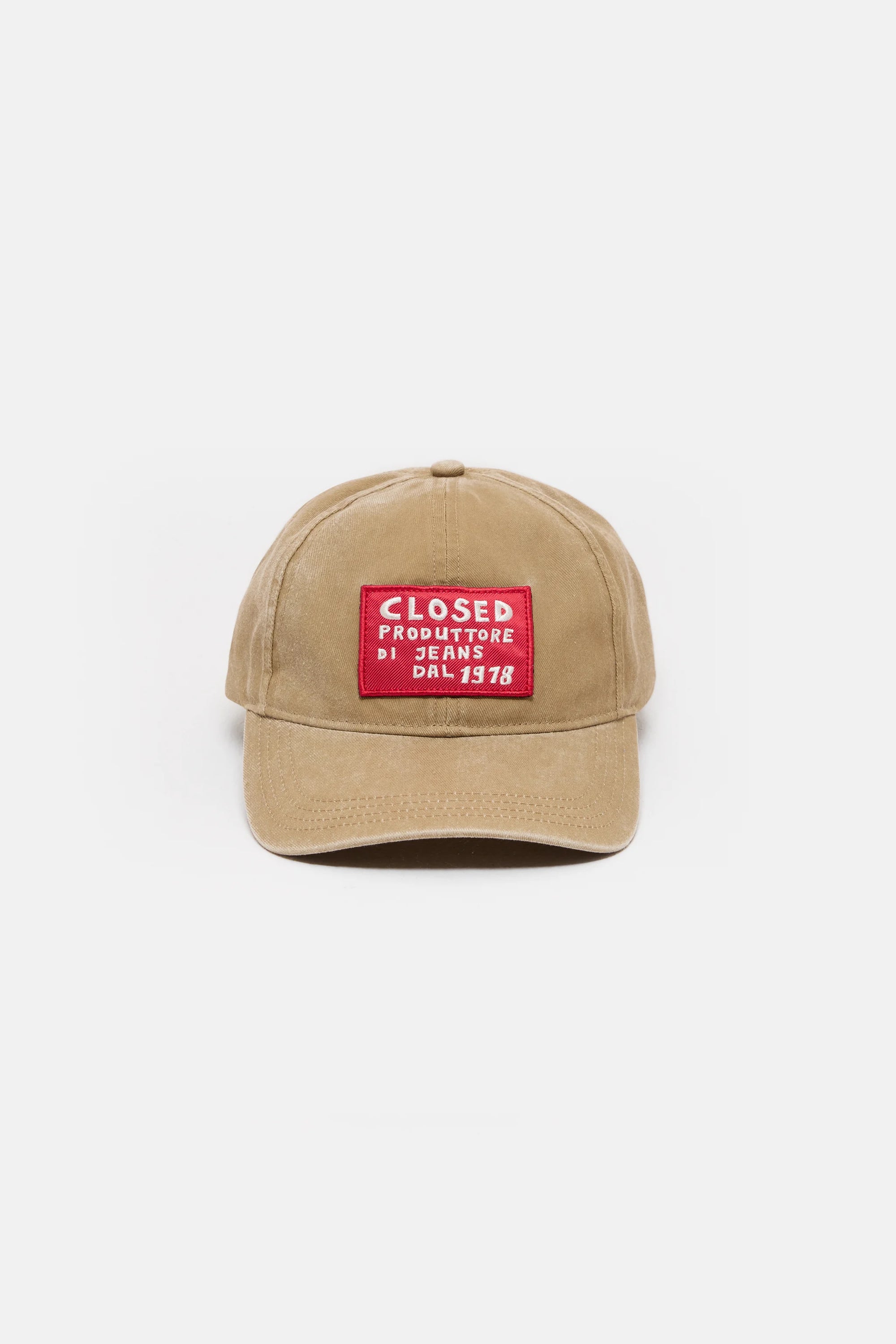 The CLOSED Cap is tan cotton with a curved brim and washed finish, featuring a bold red and white rectangular "CLOSED PRODUTTORE DI JEANS DAL 1978" patch on the front. An adjustable strap provides a comfortable fit. Plain white background.