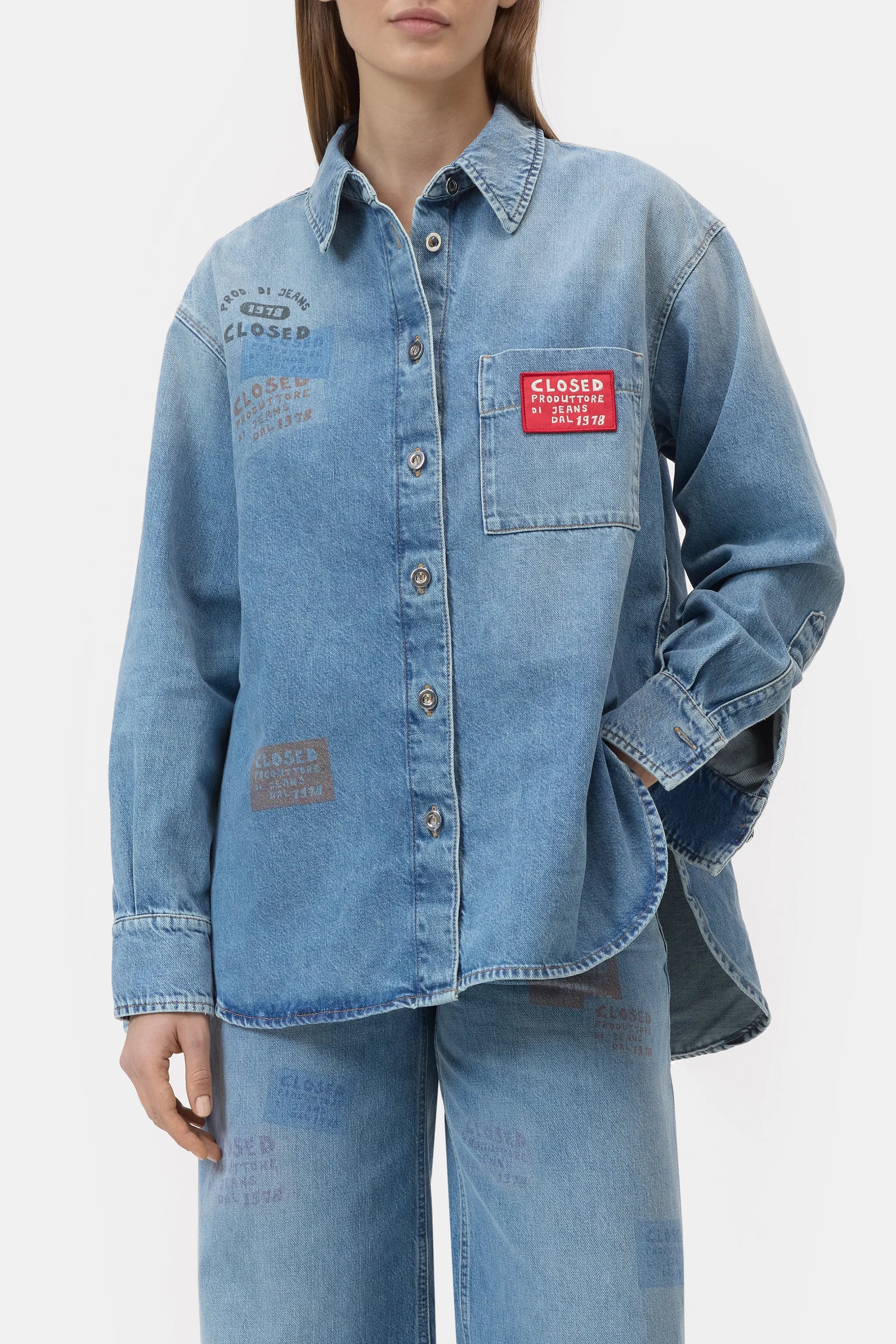 A woman wears the CLOSED Oversized Shirt and matching jeans, both with colorful printed "CLOSED" stamps and a bold red "CLOSED" patch on the chest pocket. Expertly crafted in Italy.