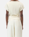 A person is seen from the back wearing CLOSED's Off Shoulder Top in light cream with short sleeves and matching wide-leg pants, set against a plain white background.