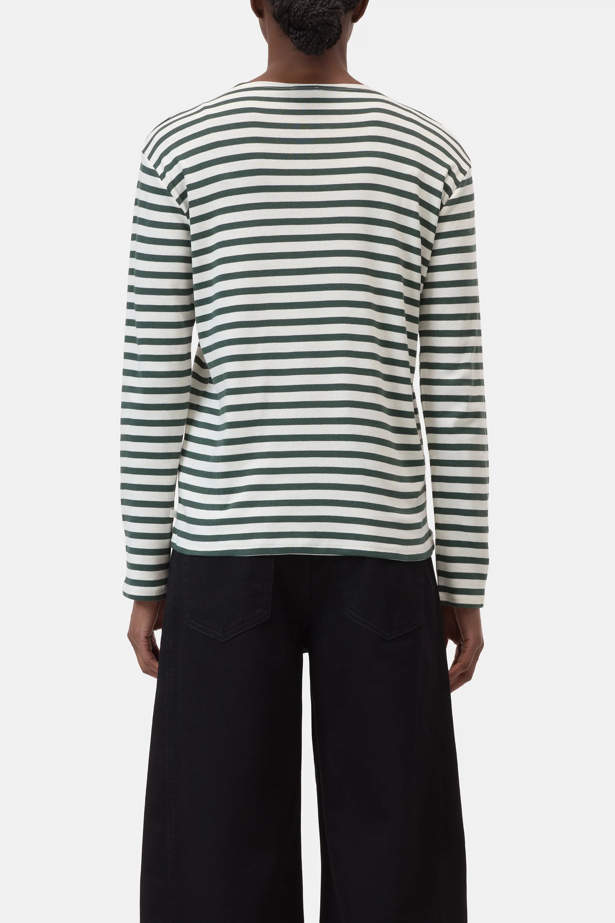 A person stands with their back to the camera, wearing CLOSED's Basic Long Sleeve Tee and black wide-leg pants, set against a plain white background.