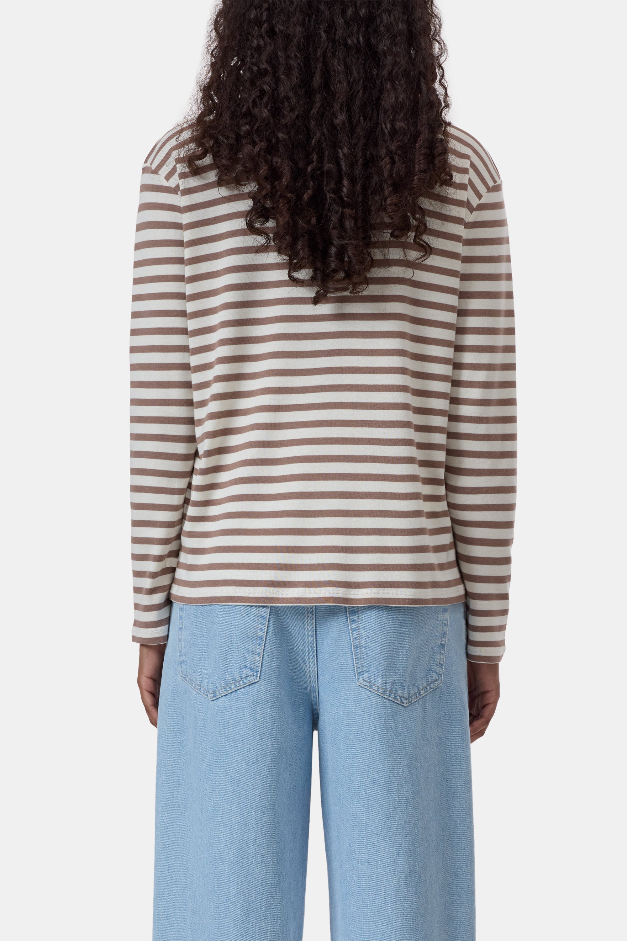 Beige and white ribbed jersey long sleeve tee by CLOSED, shown from the back, paired with light blue jeans.