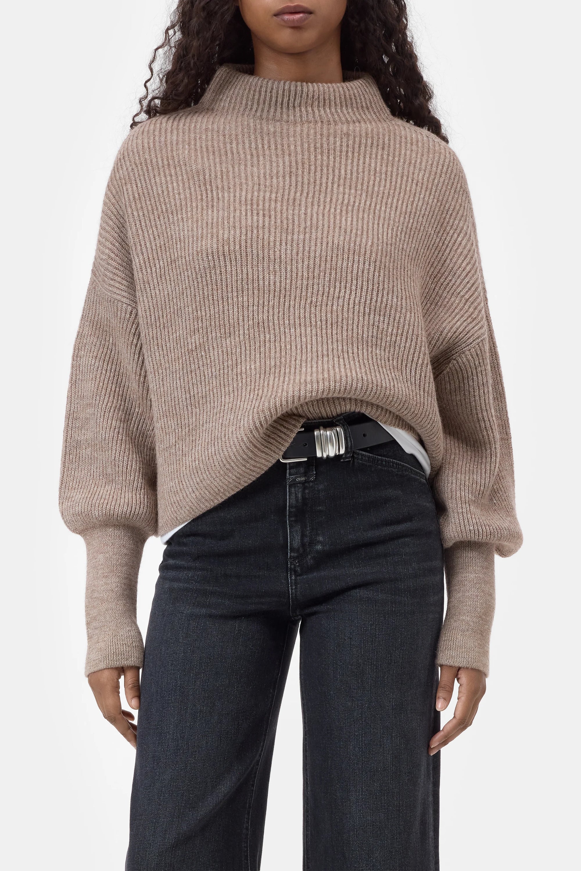 CLOSED funnel neck long sleeve top with dark jeans and black belt, minimal style against white background.