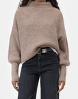 CLOSED funnel neck long sleeve top with dark jeans and black belt, minimal style against white background.