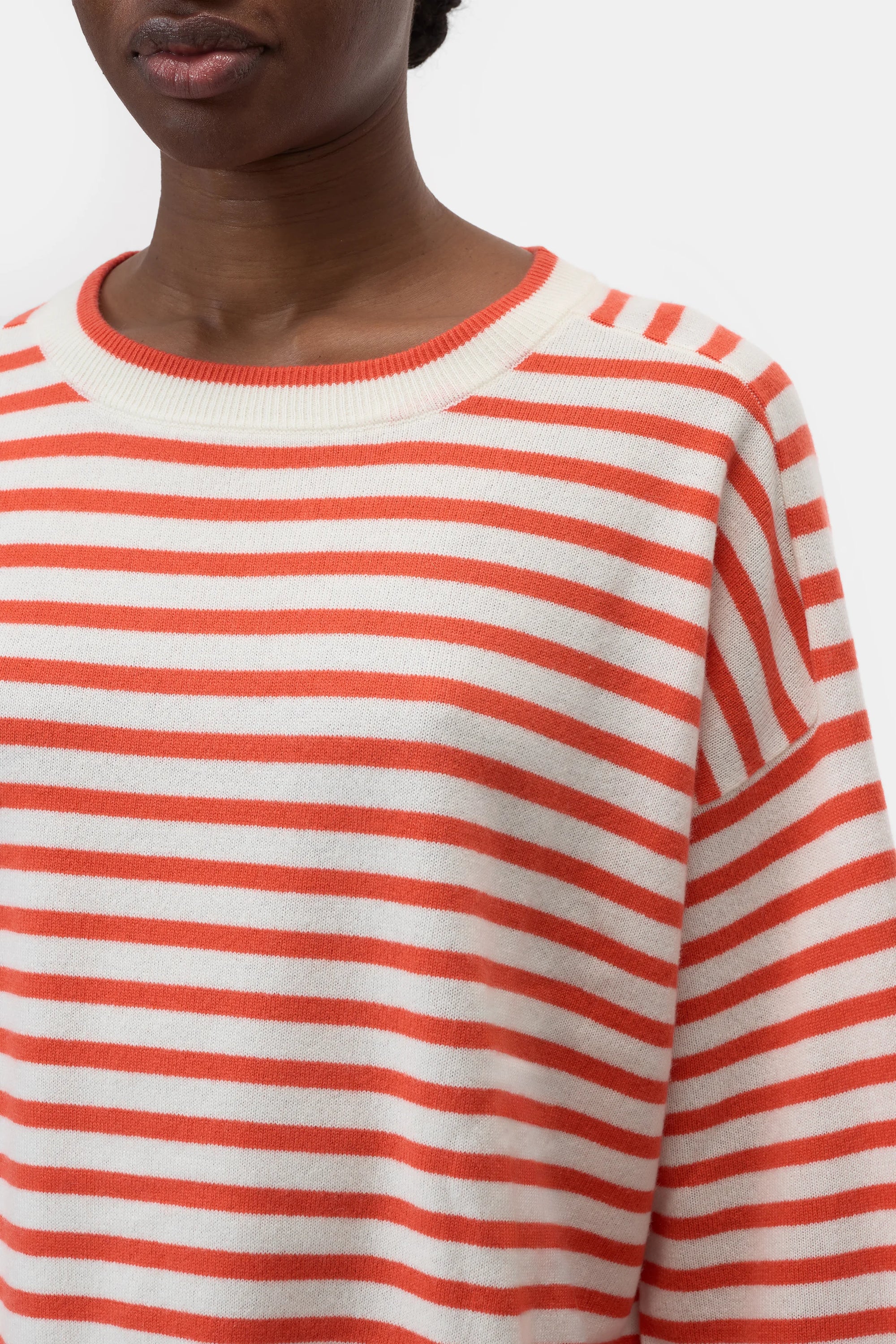 A person models the CLOSED Striped Crew Neck, a cream and orange fine-knit sweater with a round neckline, shown from shoulders to just above the mouth against a plain white background.