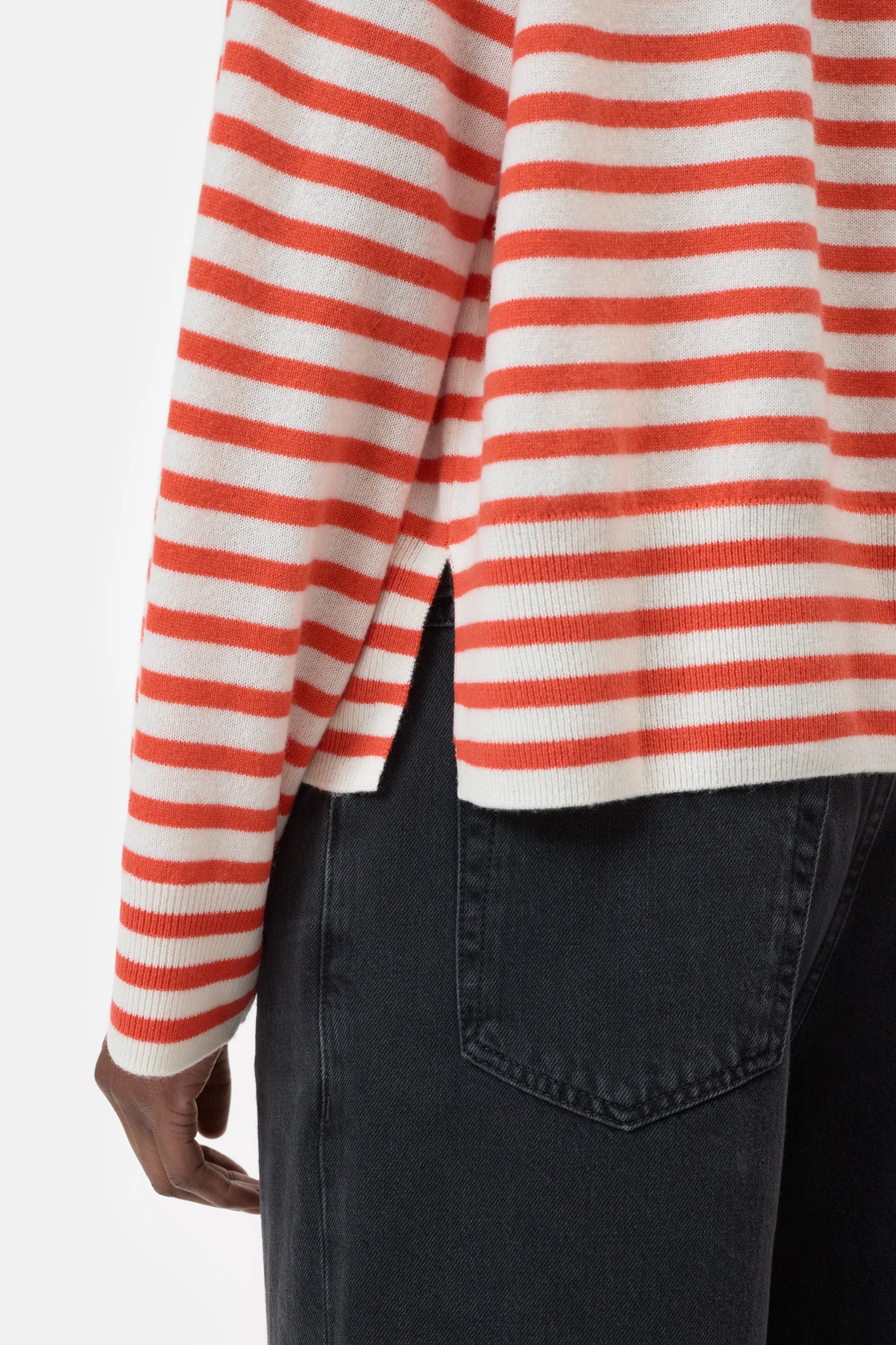 A person wearing a CLOSED Striped Crew Neck sweater with red and white stripes and side slit, paired with black jeans; only their torso and upper legs are visible.