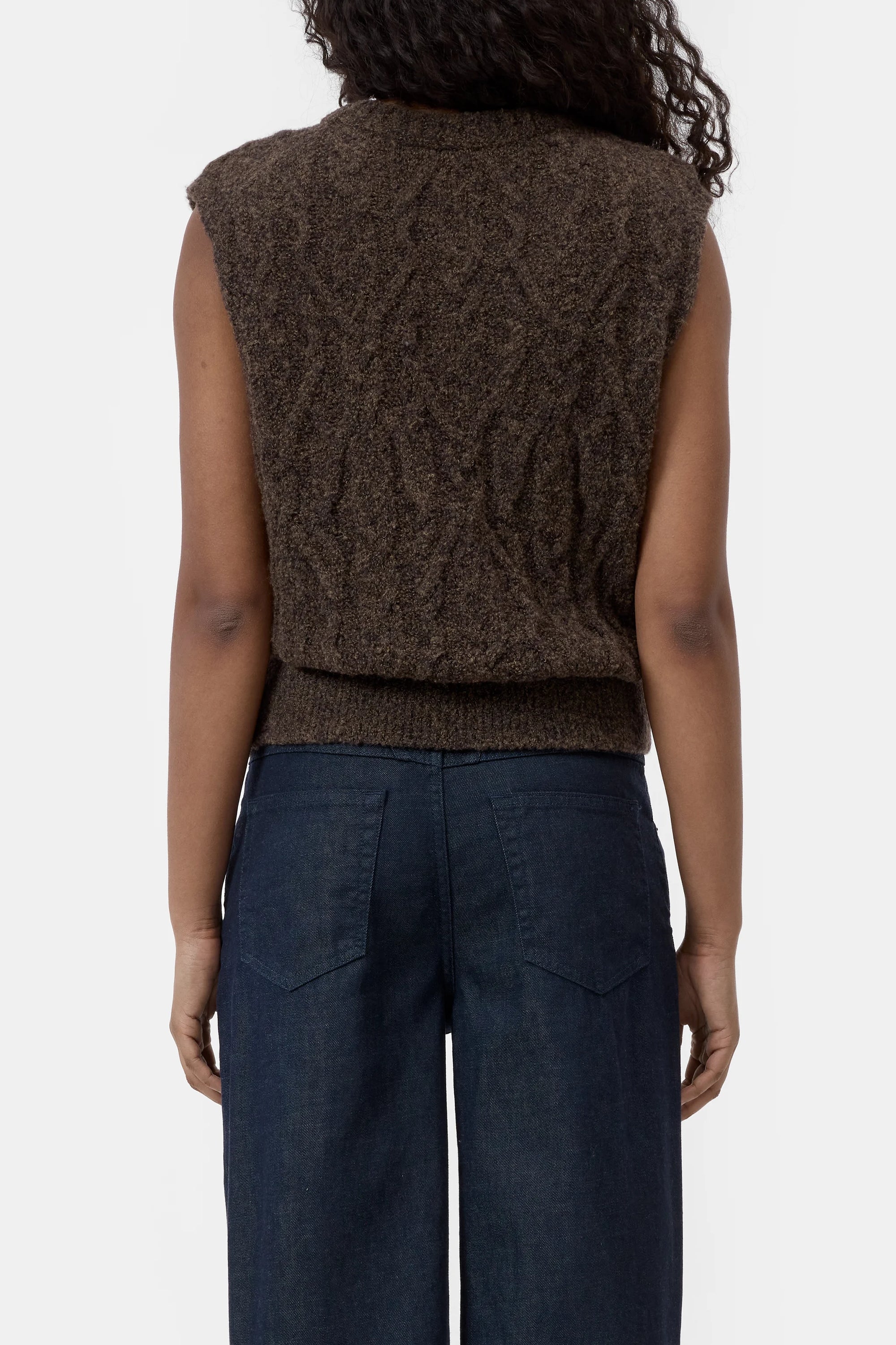Brown cable knit CLOSED vest with crew neck, styled with dark blue jeans, back view.