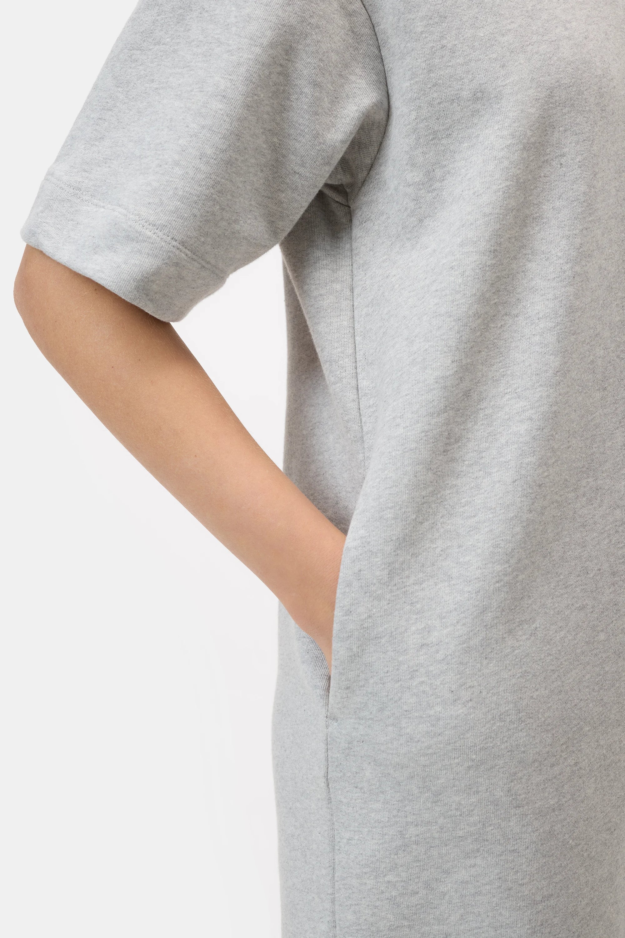 A person models the CLOSED Felpa Dress in light grey—made in Portugal from 100% cotton Felpa fabric—with a short-sleeve, shoulder to mid-thigh cut, and a hand in the side pocket, against a plain white background.