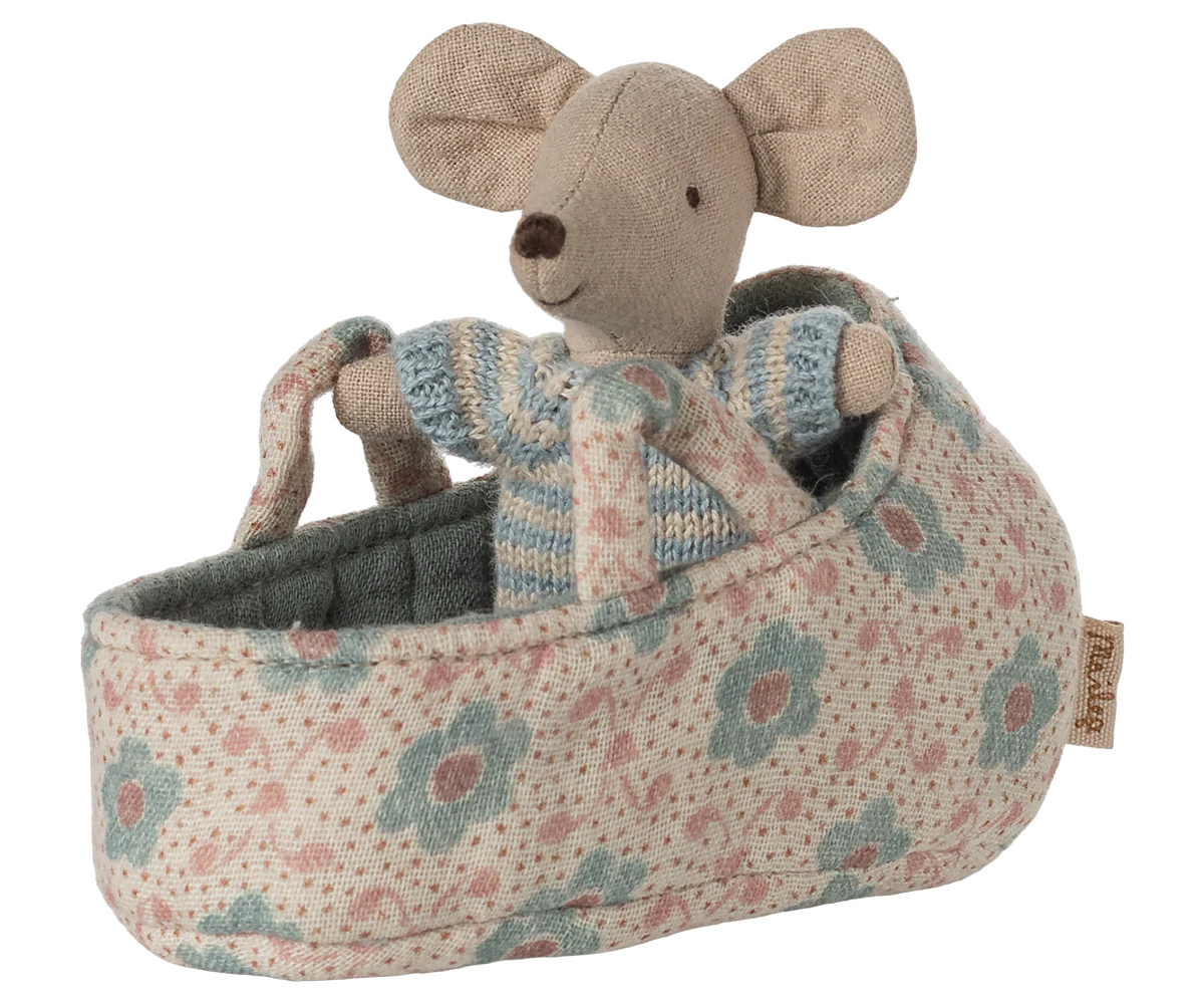 The Maileg Baby Mouse in Carry Cot by Maileg features a baby mouse in a striped sweater nestled inside a soft, floral carry cot with two handles.