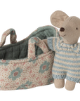 A Maileg Mouse by Maileg, dressed in a blue and white striped knitted outfit, stands beside a floral-patterned fabric basket with handles—an adorable addition to any mouse family collection.