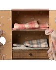 Two Maileg Ballet Mice—Little Sis in a pink tutu and headband, Little Bro in blue overalls—stand by an open toy wardrobe with floral wallpaper, folded plaid blankets, and a drawer. A charming Maileg set for any mouse house or ballet playset.