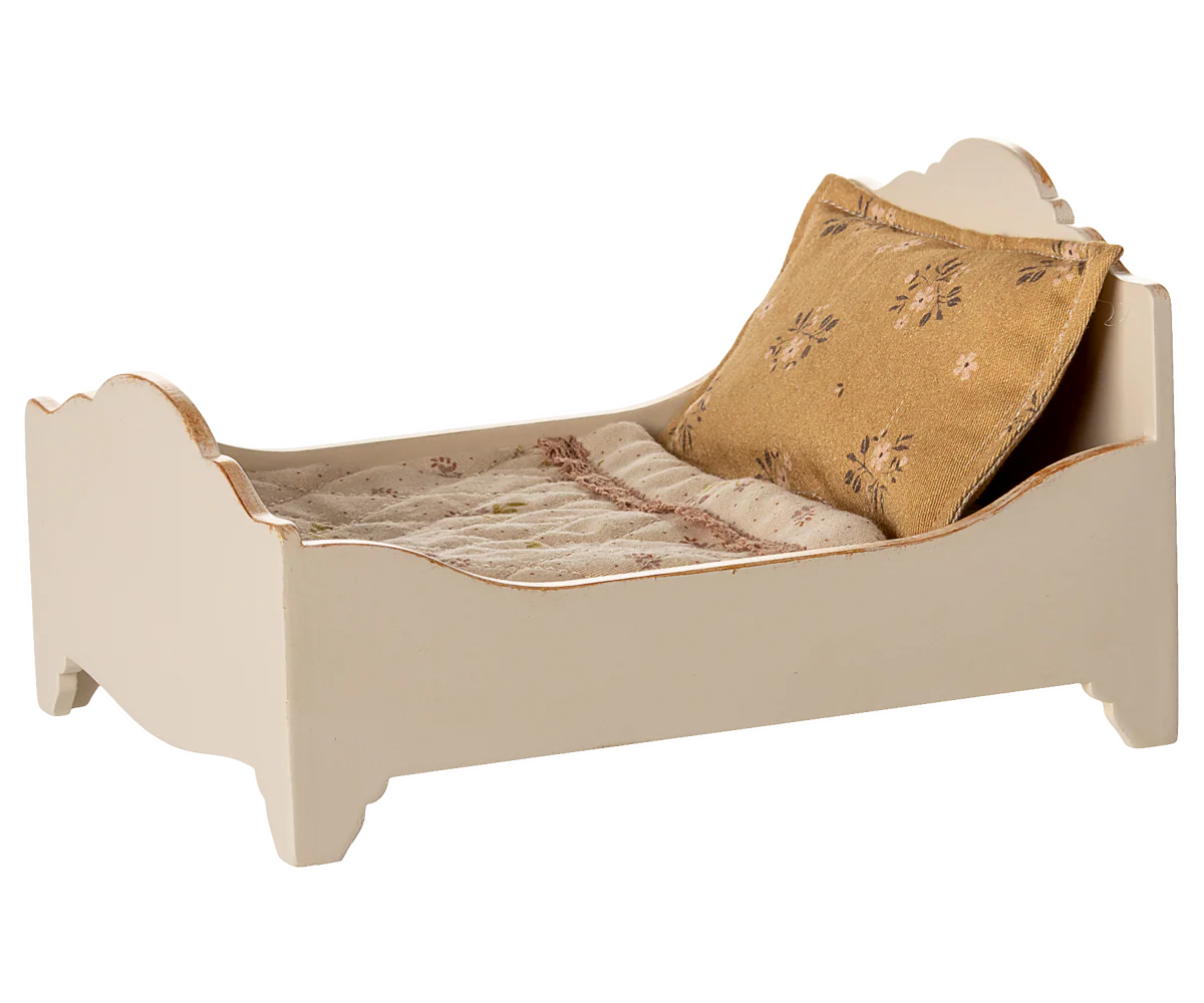 The Maileg Bed by Maileg is a small, cream-colored wooden bed for mice with a high headboard and footboard, plus a beige floral pillow and light patterned bedlinen.