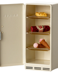 The Maileg Fridge by Maileg is a small, cream-colored metal fridge with the door open, displaying three shelves holding a bitten bread slice, salami log, lollipop, and ice cream. "MAILEG" is embossed inside the door.