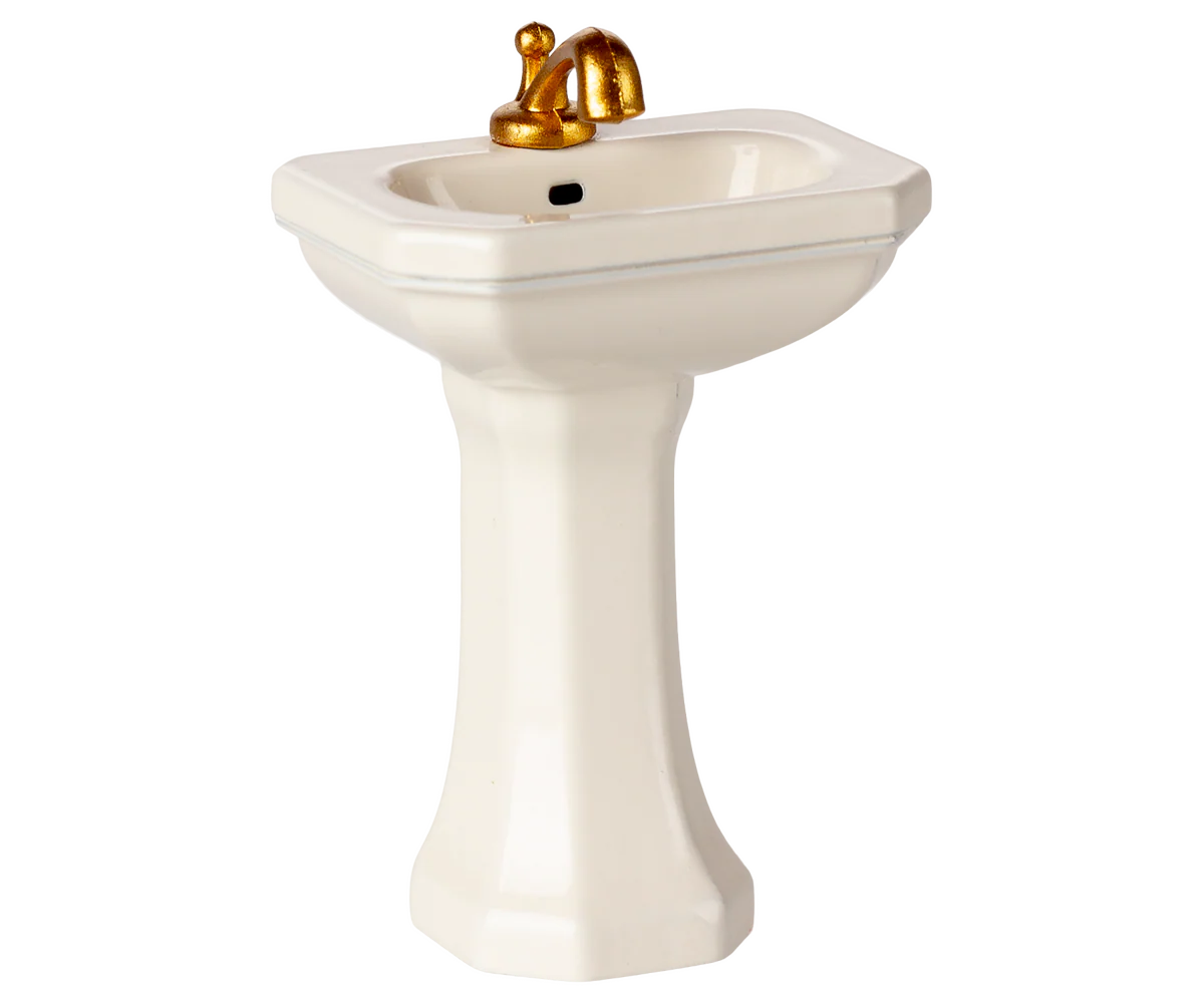 The Maileg Furniture by Maileg features a cute small white pedestal sink with a gold faucet and black drain, perfect for dollhouse or Maileg Mouse setups, shown on a plain white background.