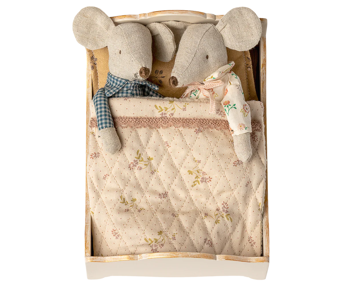Two fabric mouse dolls with sewn clothes lie snugly side by side under patterned bedlinen in a Maileg Bed by Maileg, looking cozy together.