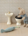 The Maileg Bathroom Sink by Maileg features a small toy mouse in a striped shirt, a miniature toilet and sink, plus tiny accessories—a perfect, charming addition to any dollhouse bathroom.