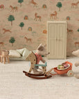 Two toy mice in a miniature room: one rides a wooden rocking horse, the other pushes a wheelbarrow with macarons. Toy furniture and the Maileg Vintage Floor Lamp by Maileg complete the scene, set against wallpaper with horses, rainbows, and trees.