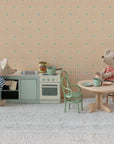 Two toy mice in striped shirts are in a Maileg kitchen scene. One stands at the Maileg Kitchen counter, while the other sits at a round table with a cup. Miniature kitchen items and chairs complete the look, styled by SuitCasa.