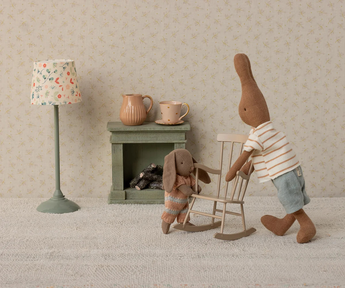 Maileg stuffed bunnies in a cozy miniature room featuring a rocking chair, lamp, and fireplace for Bungalow display.