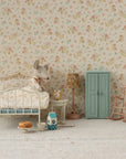 A miniature bedroom scene featuring a white metal bed, mouse plush doll under a floral quilt, small table with tea set and cake, floral lamp, pink rocking chair, clock, and the Maileg Closet by Maileg—a blue armoire with golden hangers.