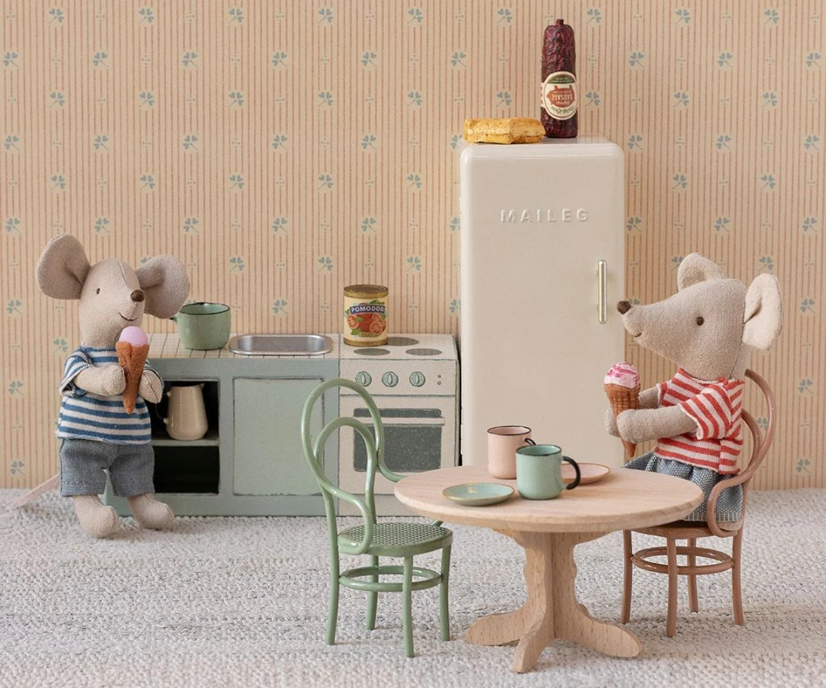 Two Maileg mice enjoy ice cream in a miniature kitchen with the Maileg Fridge, tiny food items, cups, and pastel wallpaper—a charming scene perfect for your Maileg Mouse hole Farmhouse display.