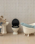 A Maileg toy mouse in a striped shirt stands by a sink and toilet, while a plush seal lounges in a clawfoot tub—creating the perfect dollhouse bathroom scene to inspire imaginative play with the Maileg Fishing Set.