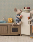 Two mice from the Maileg Fishing Set by Maileg enjoy ice cream in their mini kitchen. One sits by the fridge while the other opens the door. A toy fish, cheese, and sausage complete this charming play scene.