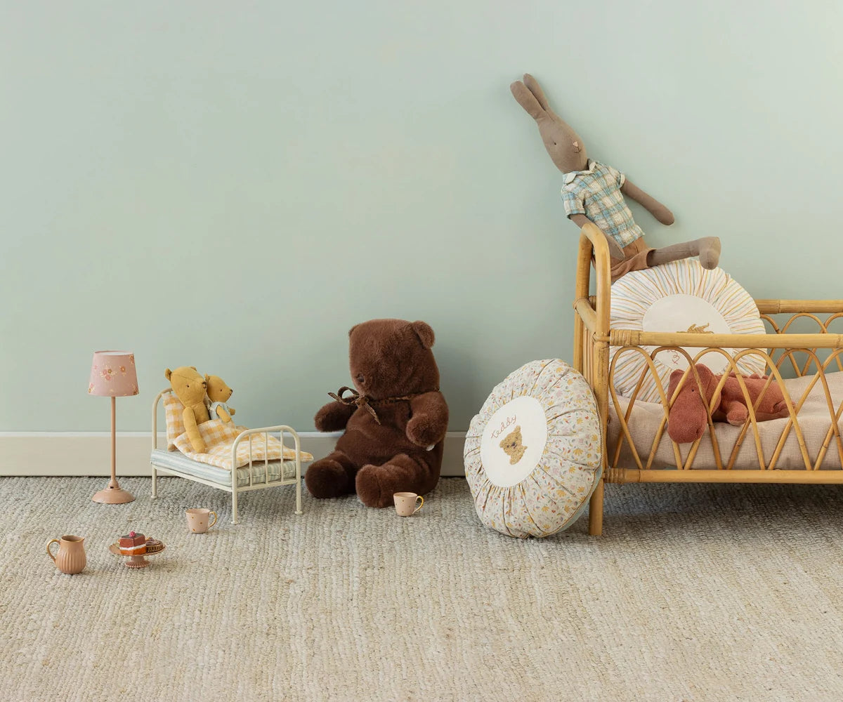 Maileg Teddy Bear Medium with soft pillows in a cozy nursery beside a rattan crib, Bungalow style setting.