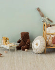 Maileg Teddy Bear Medium with soft pillows in a cozy nursery beside a rattan crib, Bungalow style setting.