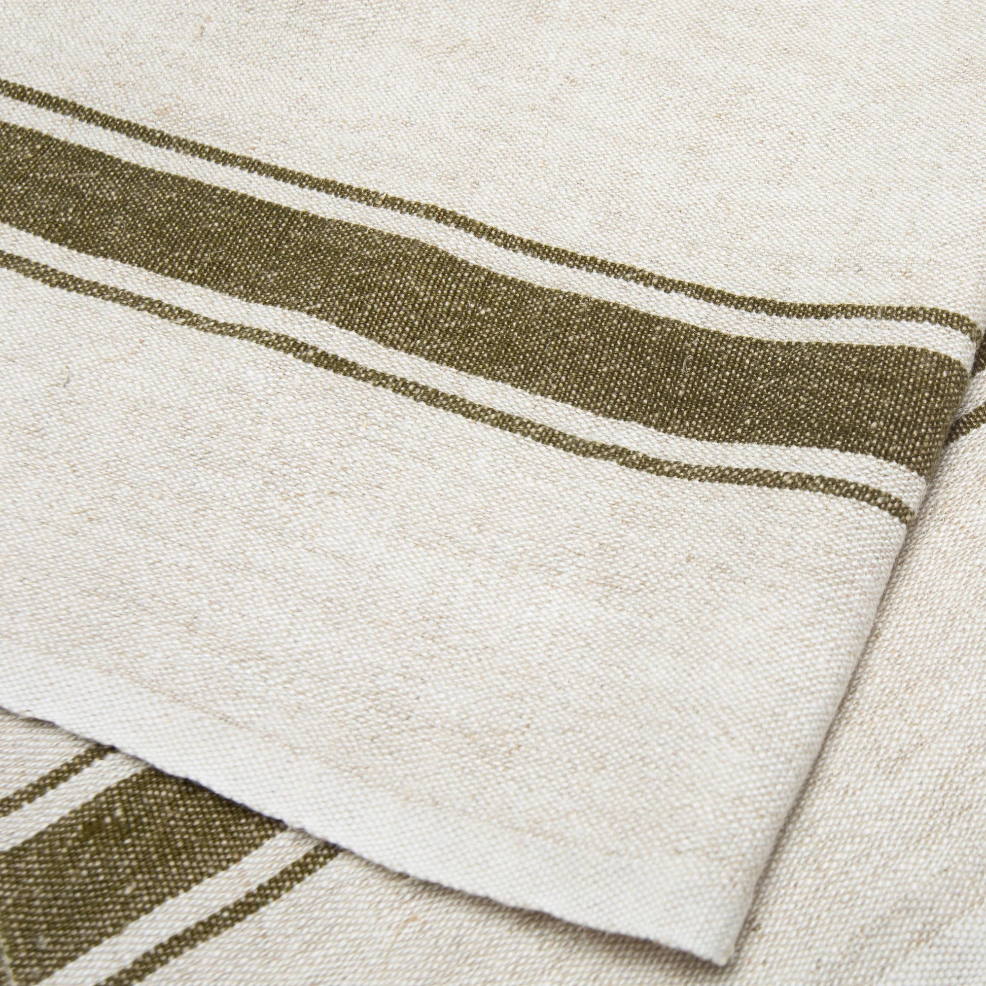 The Caravan Marseille Linen Towel Set-2 features rustic beige towels with two dark green stripes and a thinner parallel stripe, showcasing their textured weave and elegant design in a close-up view.
