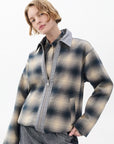 A person with short, wavy blonde hair wears the Rag & Bone carrie reversible jacket in gray and beige plaid over a matching shirt and gray pants, standing against a plain light background.