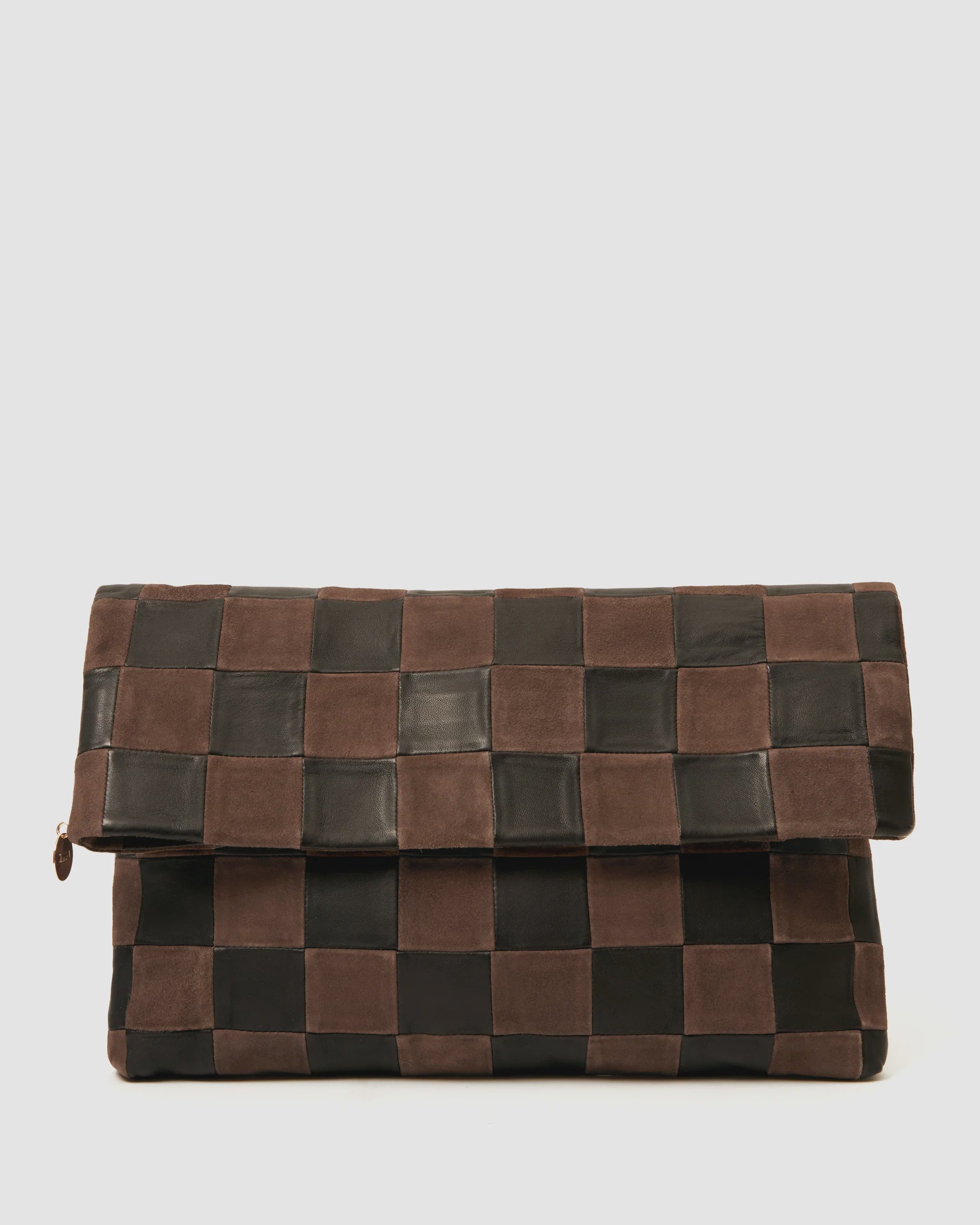 The Clare Vivier Carryall Clutch w/ Tabs showcases a dark brown and black checkerboard pattern, fold-over flap with magnetic closure, minimalist design, and chambray-lined interior for an elegant touch.