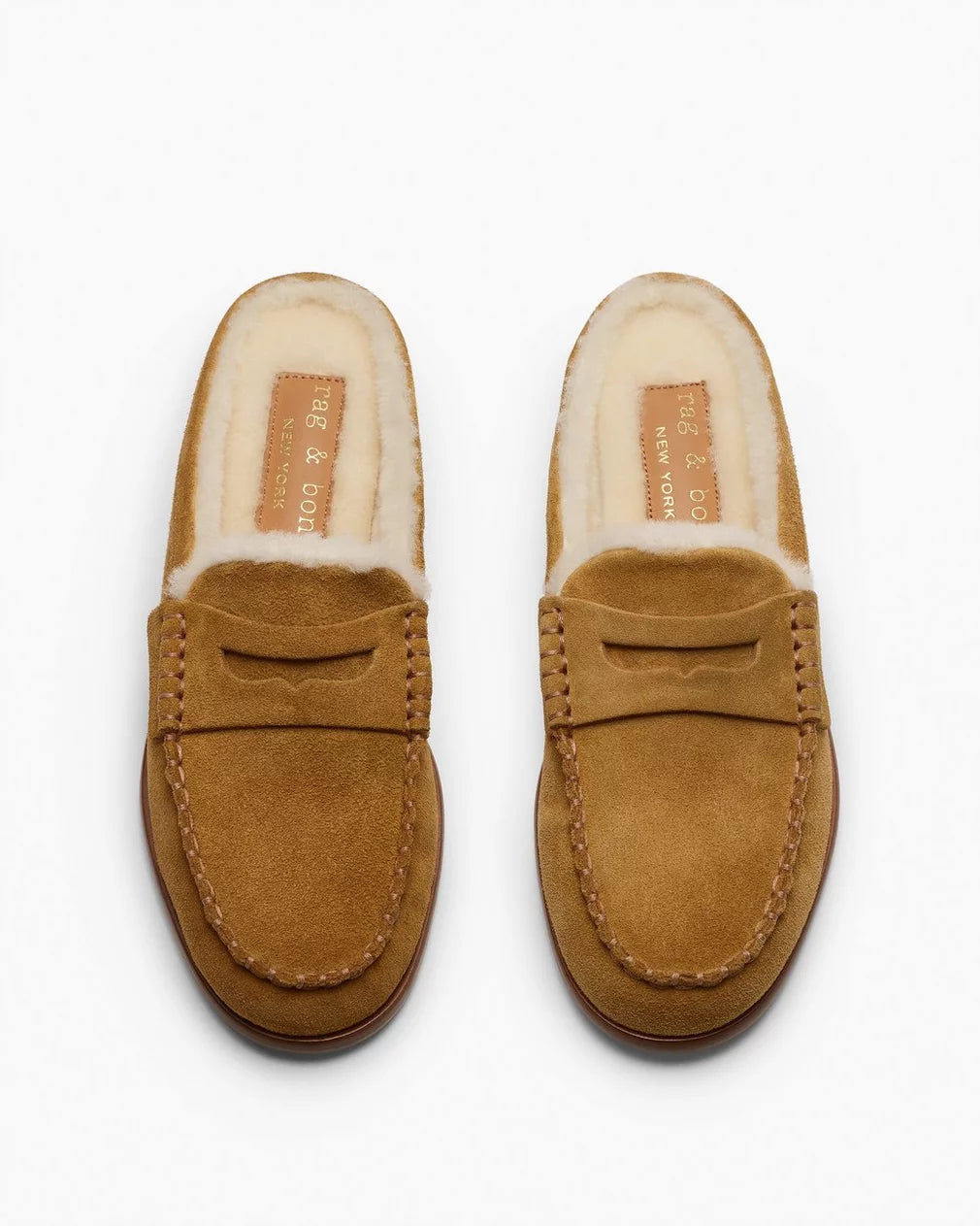 The Rag &amp; Bone Carter Mule slip-on loafers, crafted from tan Italian-milled suede with visible stitching and soft cream shearling lining, are shown side by side on a white background.