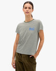 Clare Vivier Classic Tee OUI in Army Cream paired with green pants, casual style, hand-in-pocket pose.